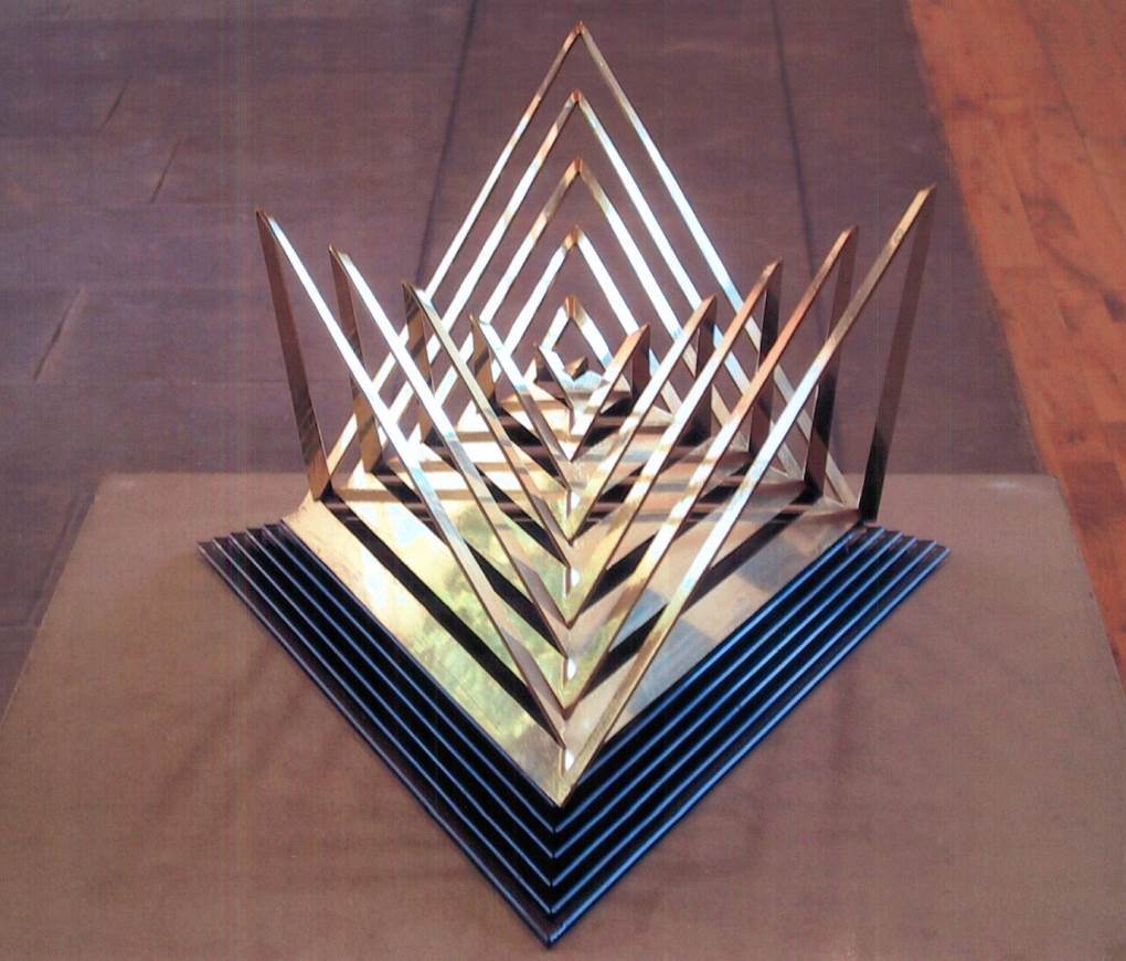Geometric sculpture cut in brass, a pyramid formed from a square.